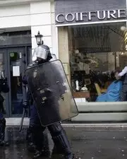 Malgré les manifestations dans sa rue, ce coiffeur, professionnel jusqu'au bout, continue à coiffer son client !